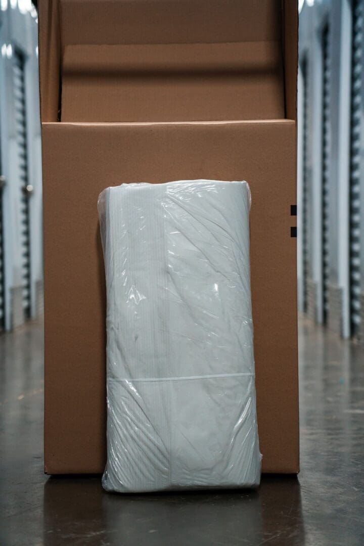 A box with a roll of toilet paper wrapped in plastic.